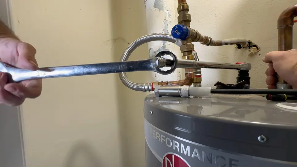 Wrench tightening a fitting on top of a tank water heater